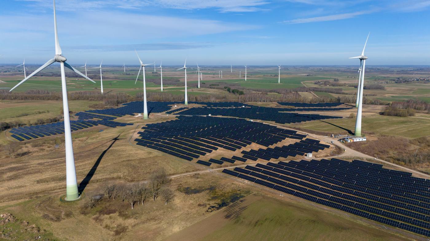 Aerial view of wind turbines and a solar park operating together as one renewable energy site