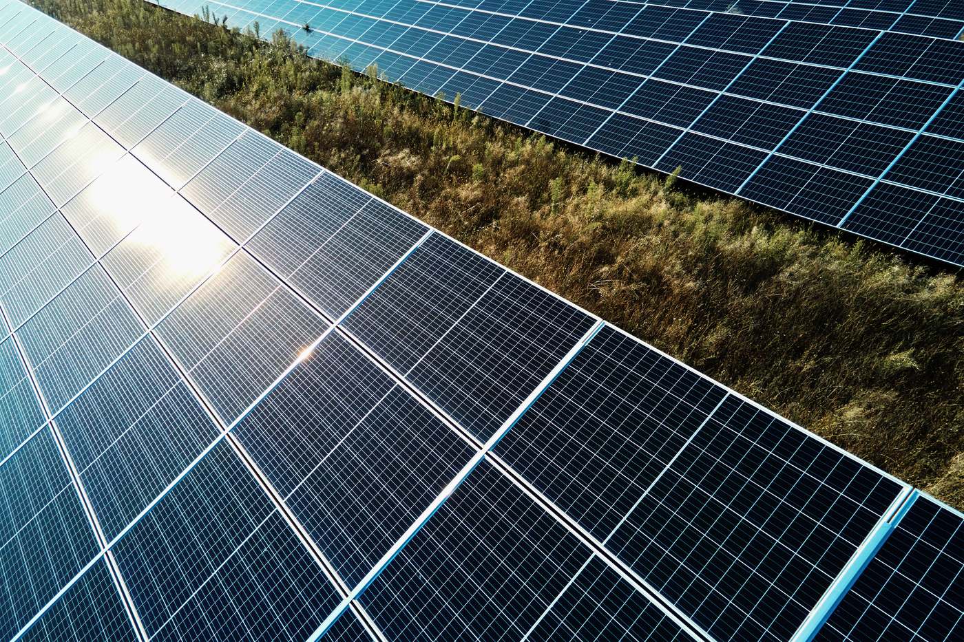 Close-up aerial view of solar panels reflecting sunlight across a field